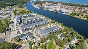 Vista aérea de un pueblo costero con un puerto deportivo, edificios modernos y un río.