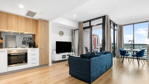 A modern living room with a sofa, TV, and dining area.
