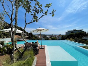 A swimming pool with lounge chairs and umbrellas, surrounded by trees and overlooking a residential area. - Apartment at Palmetto Condo by Lofty (Karon)