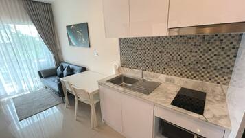 A modern kitchen with a built-in stove, a sink, and a dining area with a table and chairs.