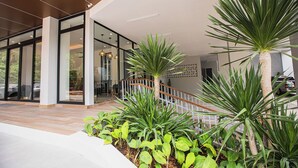 A modern building with glass doors, a wooden staircase, and various green plants. - Apartment at Palmetto Condo by Lofty (Karon)