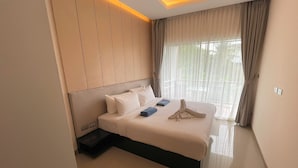 A modern hotel room with a large bed, a built-in headboard, and a view of greenery through sheer curtains. - Apartment at Palmetto Condo by Lofty (Karon)