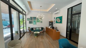 A modern reception area with a wooden reception desk, a green sofa, and a blue chair. - Apartment at Palmetto Condo by Lofty (Karon)