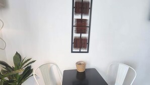 A room with a white wall, a black table with a woven basket, and two white chairs. - Oceanfront Efficiency T609 (Myrtle Beach)