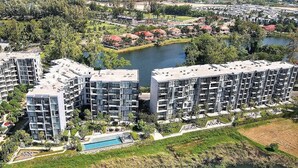 Ein moderner Apartmentkomplex mit mehreren Hochhäusern, einem zentralen Innenhof und einem Schwimmbad.