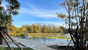 Ein ruhiger Außenbereich mit Swimmingpool, Laube und Blick auf einen von Bäumen umgebenen See.