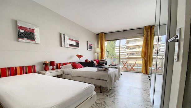 Une chambre d’hôtel avec deux lits, un balcon avec des rideaux jaunes et une vue sur la ville.