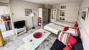 Un espace de vie compact comprenant un canapé, une petite table basse, un téléviseur, une armoire et un mini-réfrigérateur.