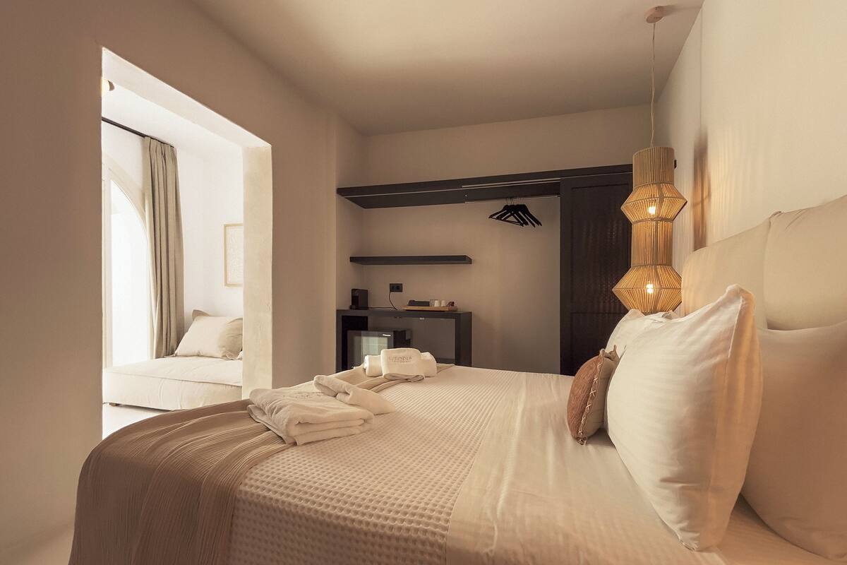 Une chambre d’hôtel avec un lit, une table de chevet, une lampe et une fenêtre avec des rideaux.