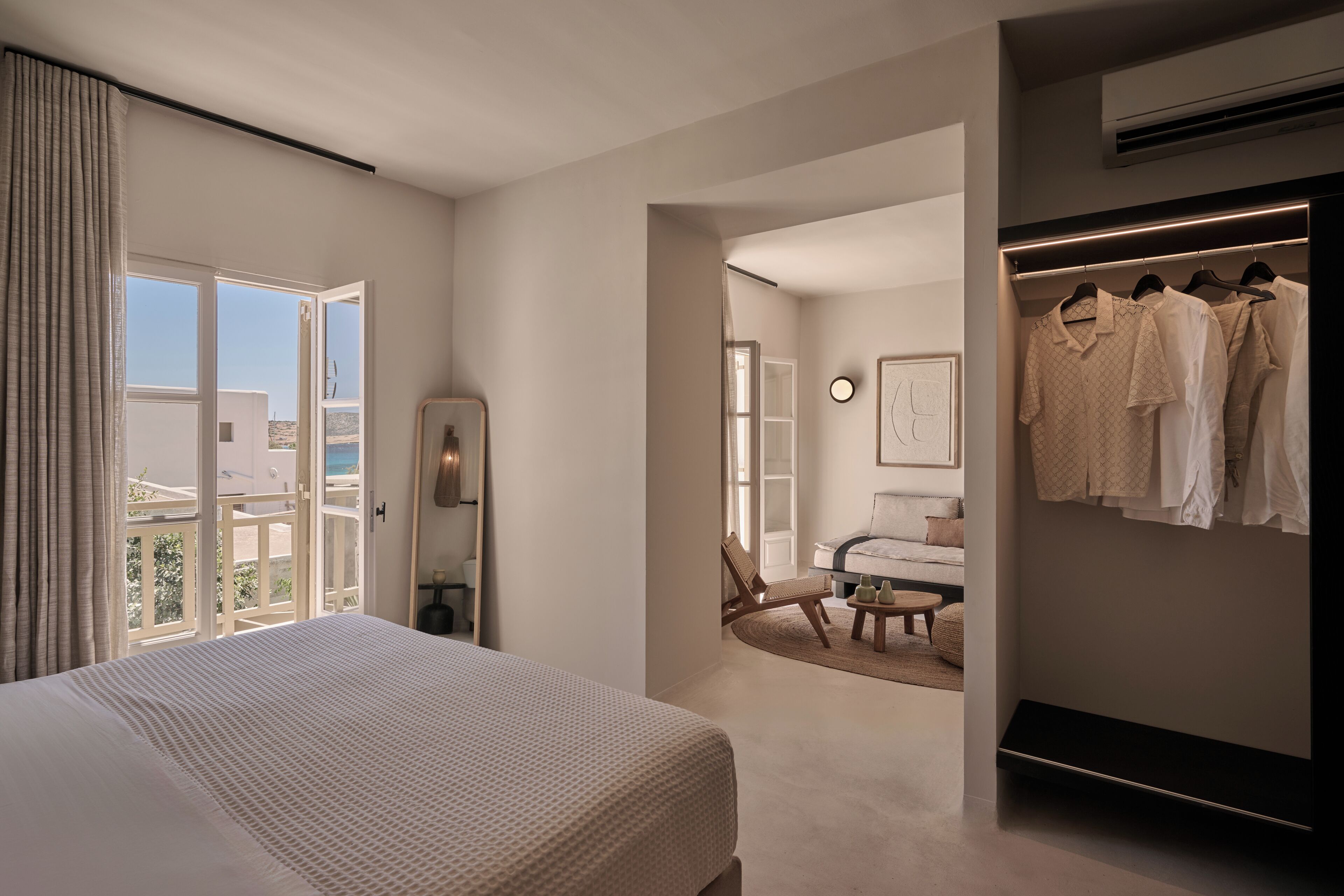 A modern hotel room with a large bed, a walk-in closet, and a view of the outdoors.