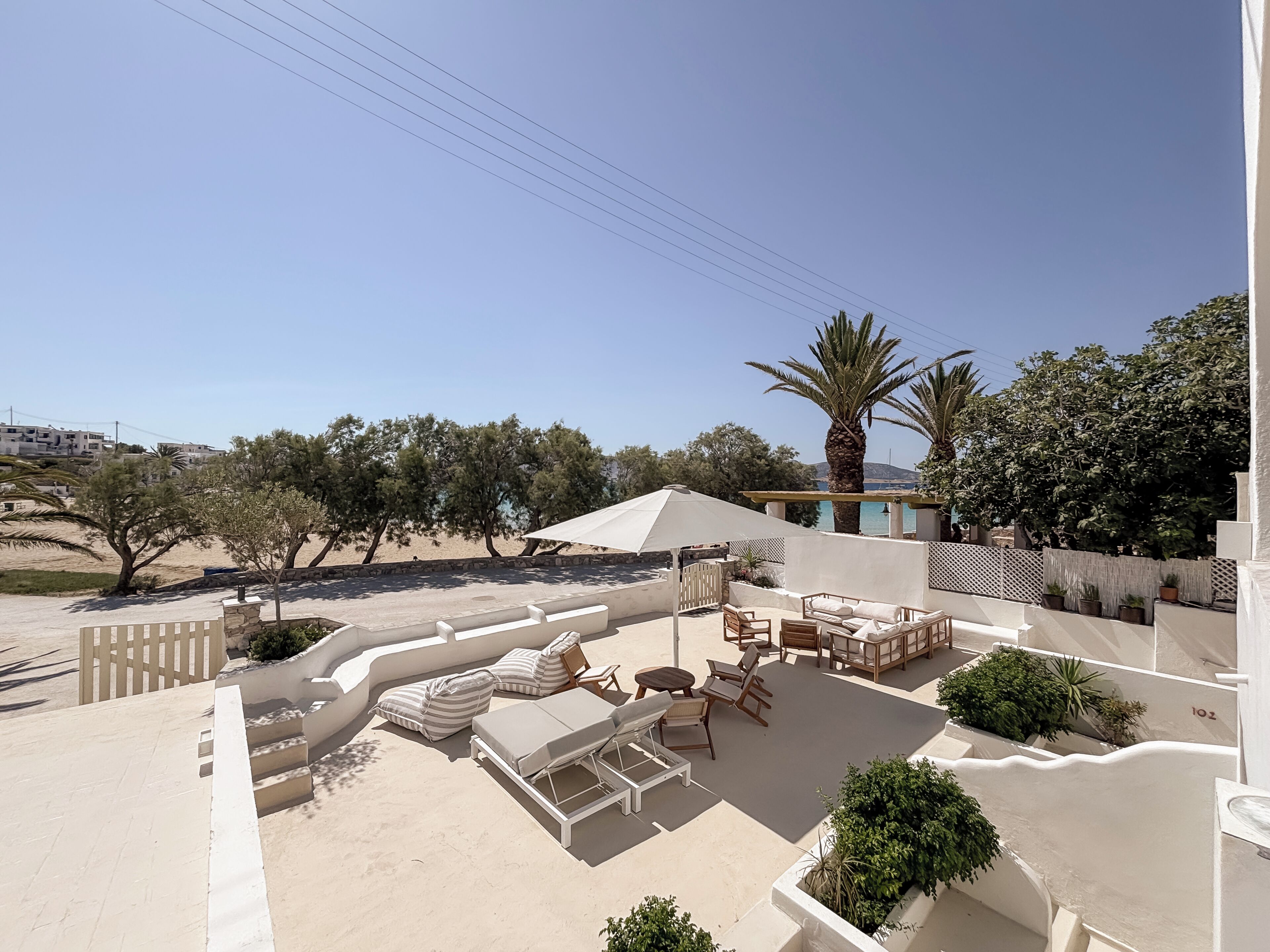 A rooftop terrace with outdoor furniture, a pergola, and a view of the beach and hills.