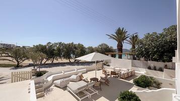 A rooftop terrace with outdoor furniture, a pergola, and a view of the beach and hills.