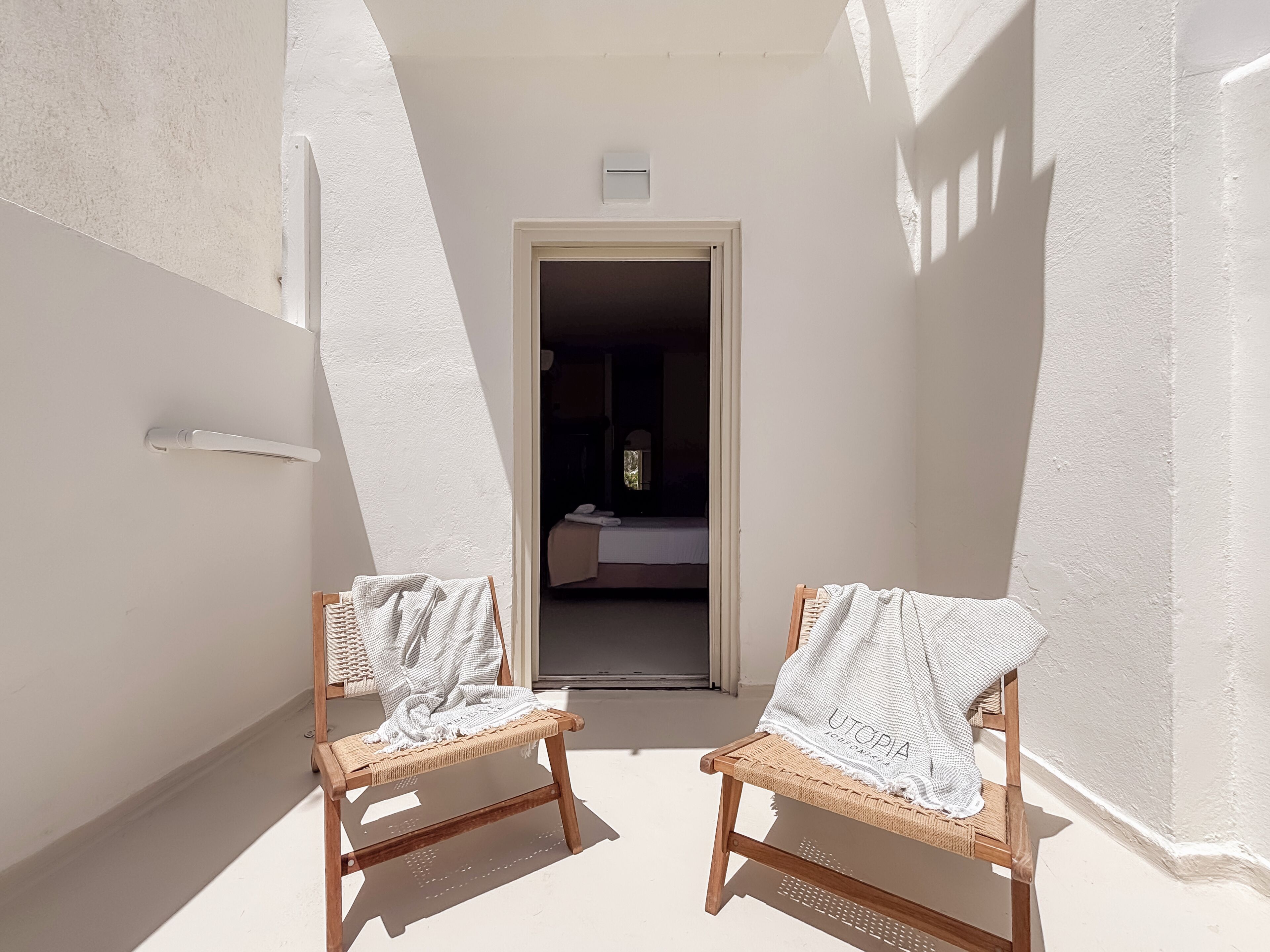 Un couloir étroit avec deux fauteuils en osier, dont l’un est agrémenté d’une serviette blanche.