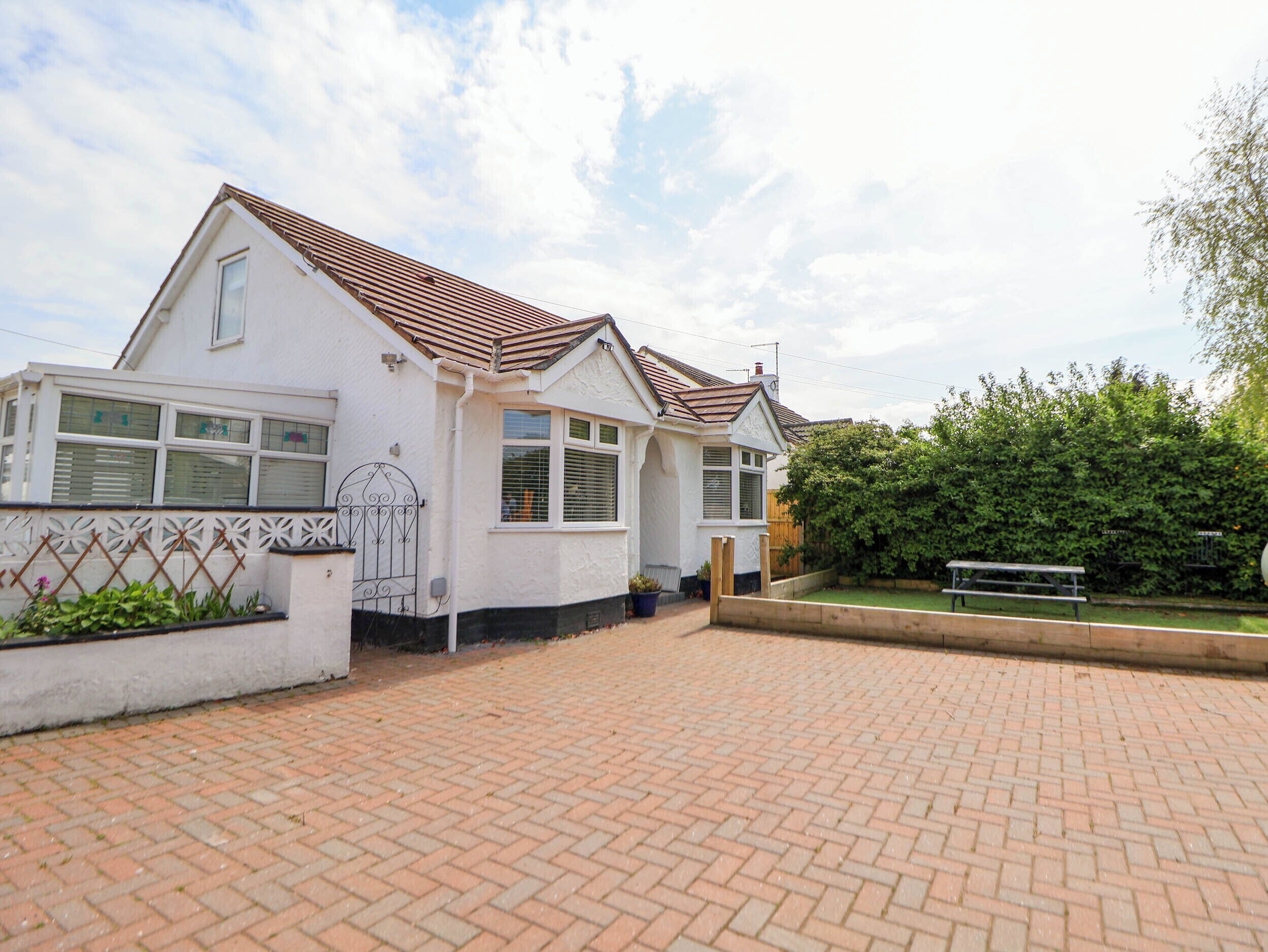 A two-story house with a tiled roof, a fenced garden, and a paved driveway.