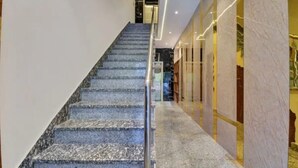Una escalera con acabado de mármol que lleva a una habitación con pared de vidrio.