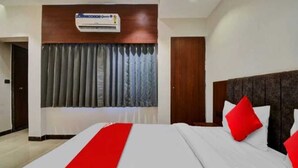 Habitación de hotel con una cama grande, cabecero de madera y una ventana con cortinas.