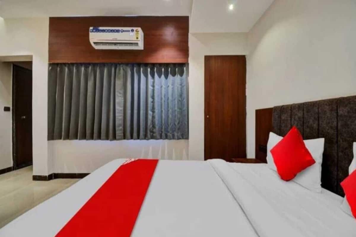 Habitación de hotel con una cama grande, cabecero de madera y una ventana con cortinas.