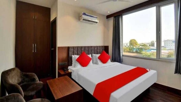 Habitación de hotel con cama, escritorio, silla, equipo de aire acondicionado y ventana con vistas.