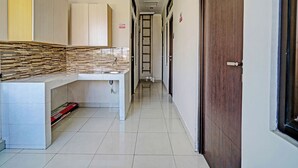 A hotel hallway with a reception desk, a tiled floor, and doors labeled with room numbers. - OYO 92768 Flagship Exclusive Colombus Near Stasiun Karawang (Karawang)