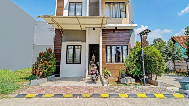 A modern two-story house with a flat roof, a covered entrance, and a visible motorcycle parked outside. - OYO 92768 Flagship Exclusive Colombus Near Stasiun Karawang (Karawang)