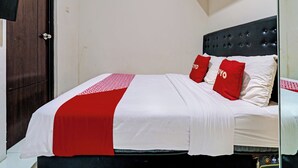 A neatly made bed with a white and red bedspread, two red pillows, and a dark headboard. - OYO 92768 Flagship Exclusive Colombus Near Stasiun Karawang (Karawang)