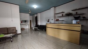 Uma sala de estar ampla com balcão de recepção, disposição de assentos e ventilador de teto.