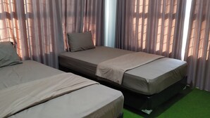 A room with two beds, each with a pillow and a blanket, and a green carpet. - Hotel O Losmen Griya Mulia Katingan Kuala (Pegatan Hilir)