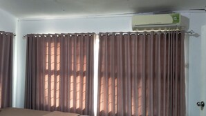 A room with a bed, curtains, an air conditioning unit, and a door. - Hotel O Losmen Griya Mulia Katingan Kuala (Pegatan Hilir)