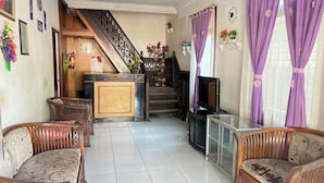 A living room with a sofa, a television, a staircase, and a reception desk. - Hotel O Losmen Griya Mulia Katingan Kuala (Pegatan Hilir)