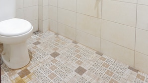 Un baño con ducha, inodoro y baldosas de suelo con diseño.