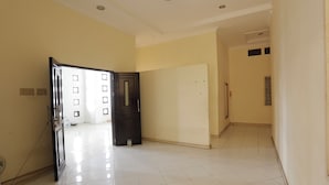 Una habitación de hotel con suelo de baldosas, una puerta y una pared con ventana.