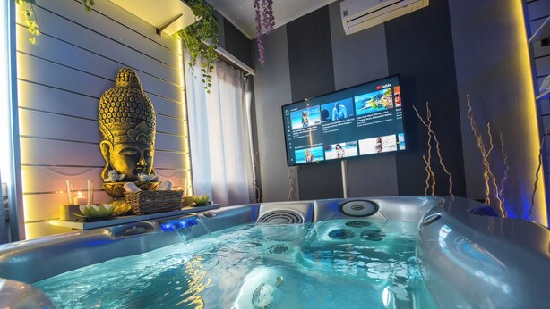 Un jacuzzi con una estatua de Buda, un televisor de pantalla plana y una decoración con flor de loto.