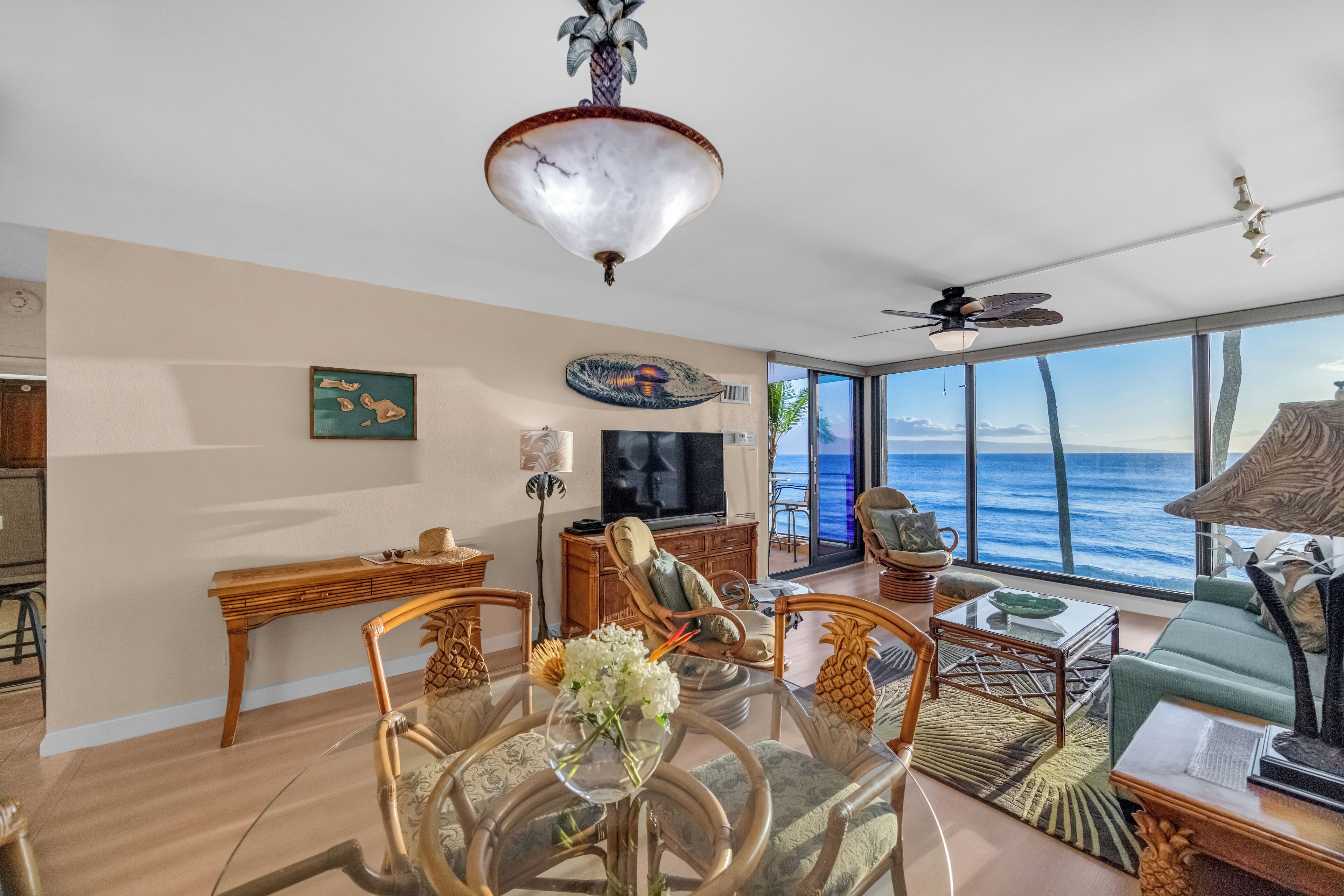 A spacious living area with a large TV, wooden furniture, and a view of the ocean.