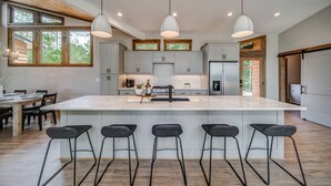 A modern kitchen with a large island, bar stools, and pendant lighting. - Amazing Grace ~ Indoor Heated Pool ~ Pickleball ~ Basketball ~ Hot Tub ~ Fire Pit (Ellijay)