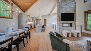 A spacious kitchen with a central island, wooden ceiling, and a stone fireplace. - Amazing Grace ~ Indoor Heated Pool ~ Pickleball ~ Basketball ~ Hot Tub ~ Fire Pit (Ellijay)