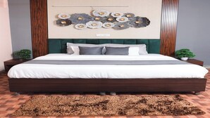 Une chambre à coucher avec un grand lit, un élément décoratif mural et une petite plante posée sur la table de chevet.