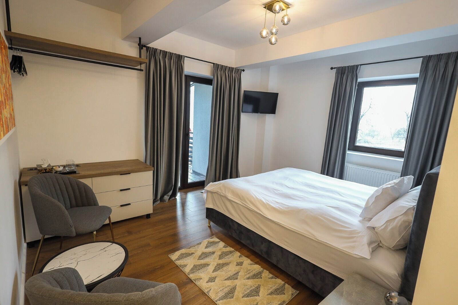 Une chambre à coucher moderne avec un lit, un bureau, une chaise et un téléviseur.
