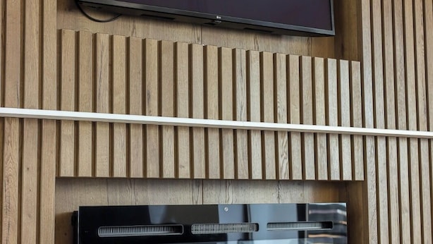 A wall-mounted television with a Netflix logo, a built-in sound system, and a wooden panel design.