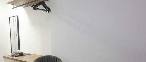 Una sala de estar moderna con un mueble de madera, dos sillones tapizados en gris, una mesa redonda de centro con tapa de mármol y una lámpara colgante.