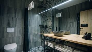 A modern bathroom with a shower, a toilet, a sink with a wooden countertop, and a mirror.