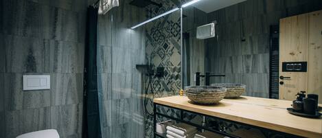 A modern bathroom with a shower, a toilet, a sink with a wooden countertop, and a mirror.