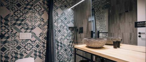 Un baño moderno con baldosas estampadas, un inodoro, un espejo grande y un tocador de madera con lavabo.
