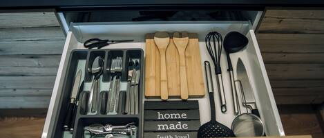 Un cajón de cocina con utensilios, como cuchillos, cucharas y un batidor.