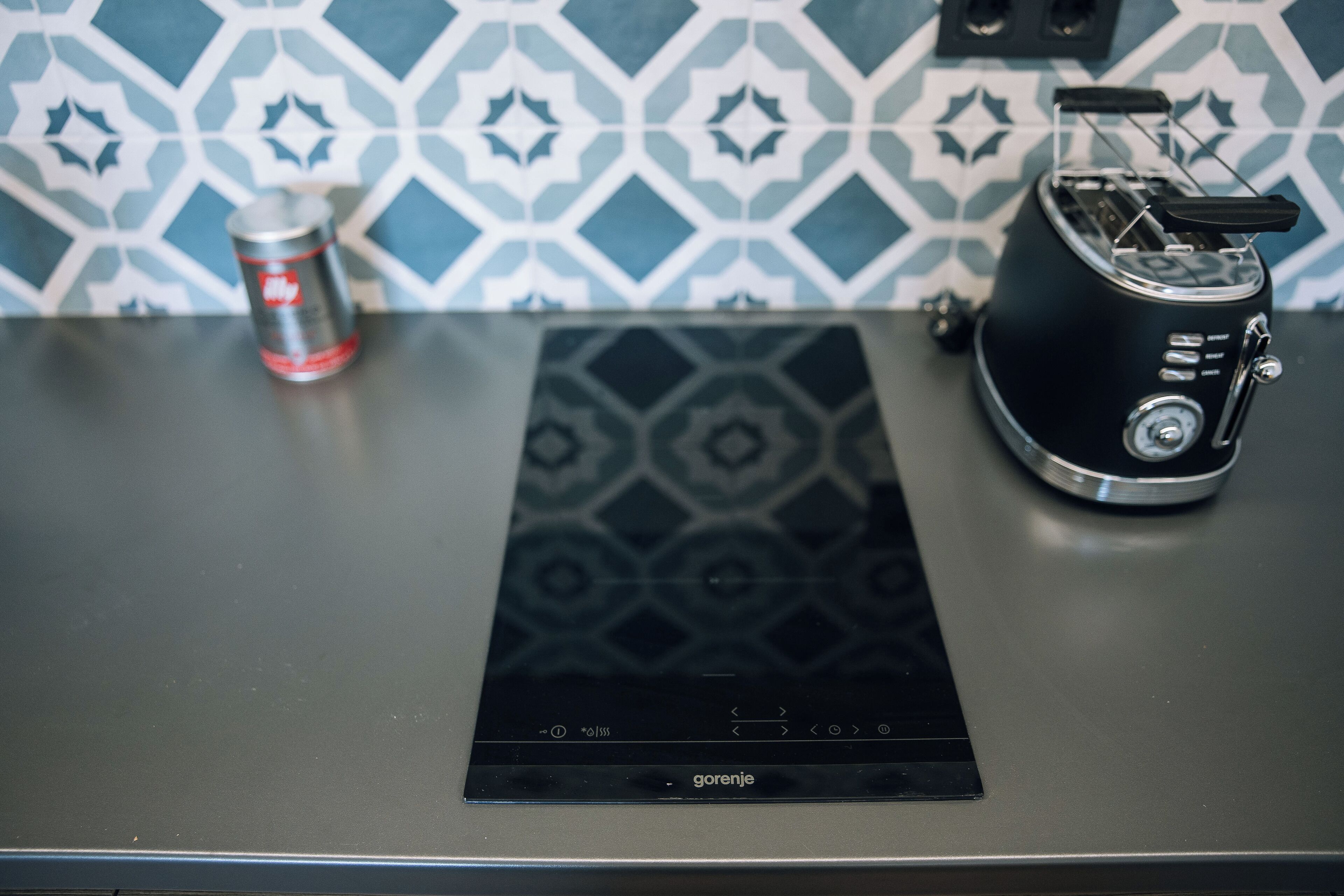 Un plan de travail de cuisine avec une plaque de cuisson à induction noire et un grille-pain.