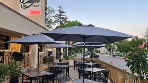 Zona de estar al aire libre con mesas y sombrillas en un restaurante llamado 'Chic Fine Cuisine'.