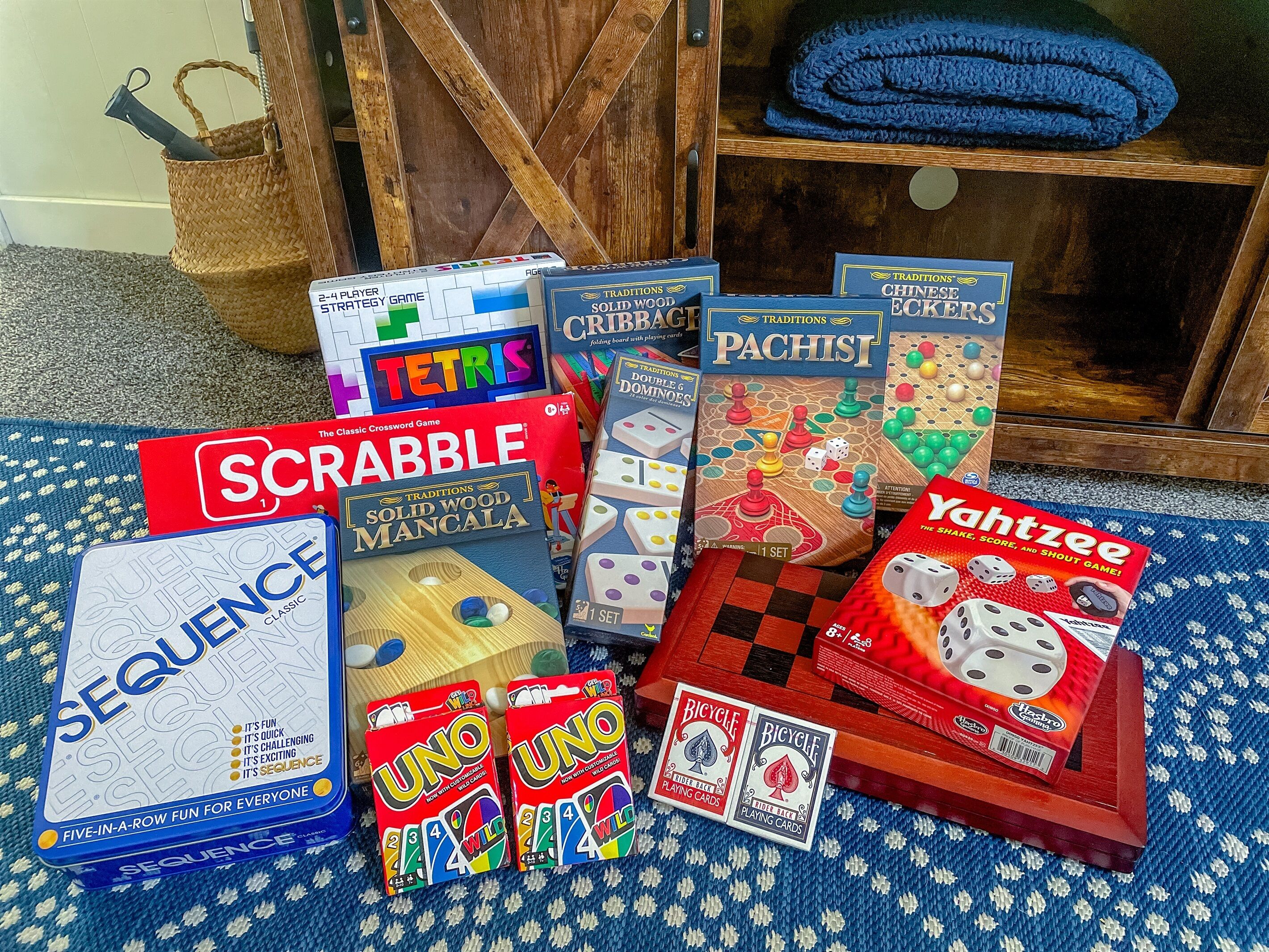 Variedad de juegos de mesa, incluyendo Scrabble, Tetris, Pachisi y otros, dispuestos sobre una alfombra estampada.