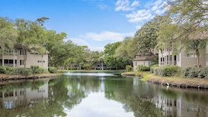 A serene riverside view with a calm water body reflecting trees and buildings.