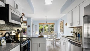 A modern kitchen with white cabinets, stainless steel appliances, and a central island.