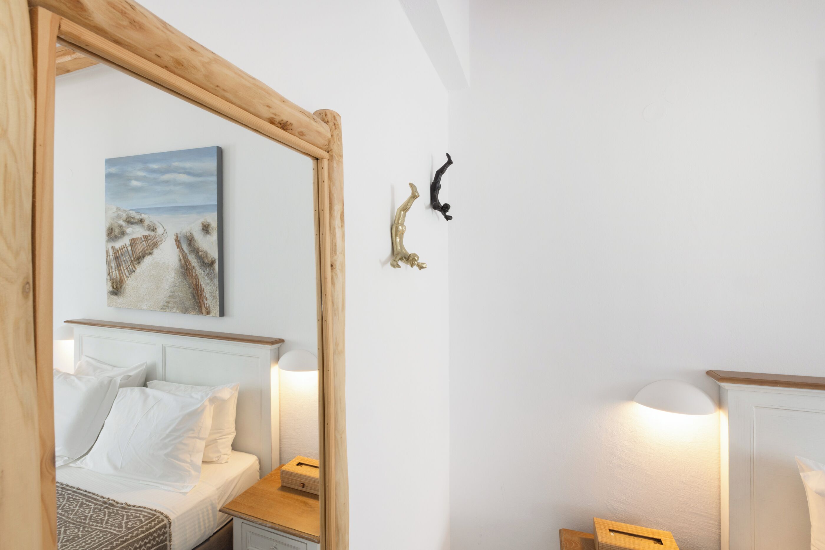 Un dormitorio con cama, mesitas de noche, espejo y lámparas de pared.