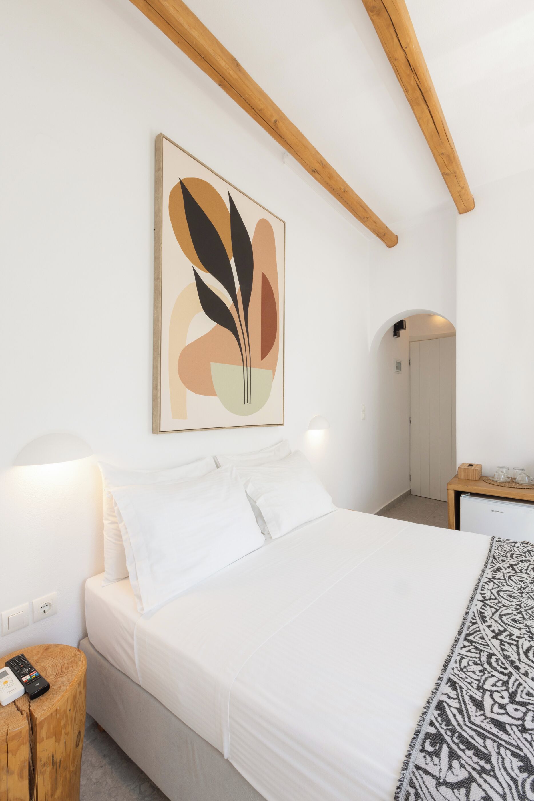 A bedroom with a bed, bedside table, lamp, and a wall-mounted artwork.